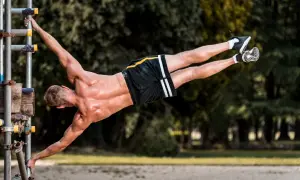 Mężczyzna wykonuje planche na drążku, demonstrując siłę i kontrolę. To dowód, że kalistenika czy siłownia – liczy się trening!