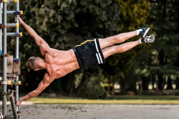 Mężczyzna wykonuje planche na drążku, demonstrując siłę i kontrolę. To dowód, że kalistenika czy siłownia – liczy się trening!
